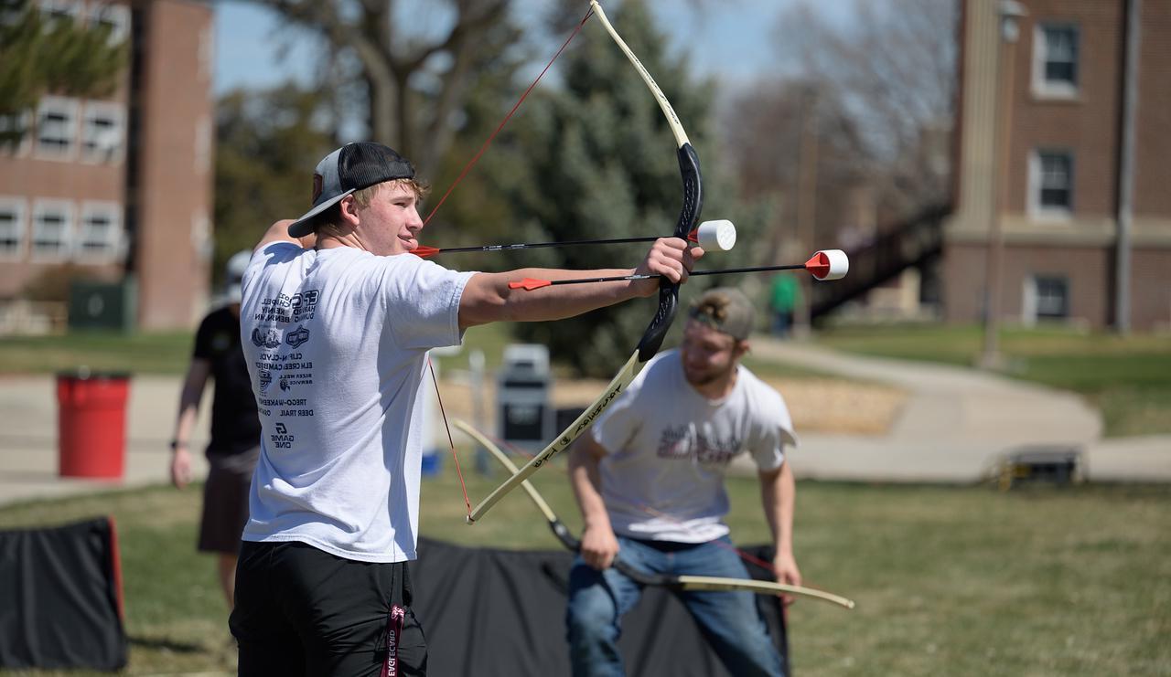 Student shooting a bow and foam arrows at the Inauguration block party